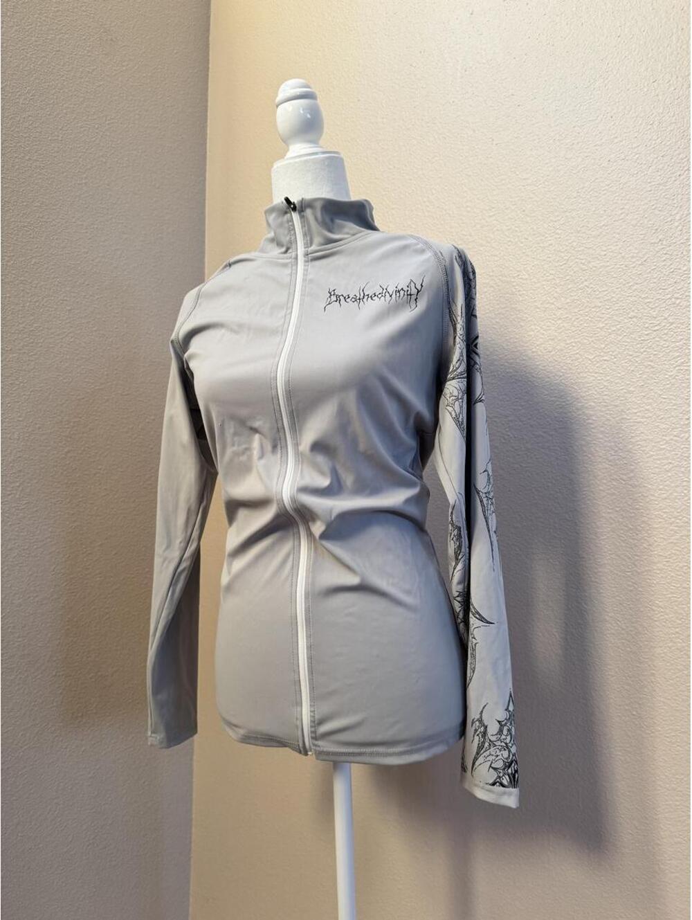 Breathe Divinity gray zip up jacket with black graphic on the sleeve
